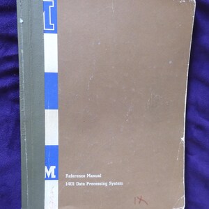 May include: A vintage reference manual for the 1401 Data Processing System. The cover is a muted brown with the text "Reference Manual" and "1401 Data Processing System". The spine has a vertical blue and white striped design with the letter "M".