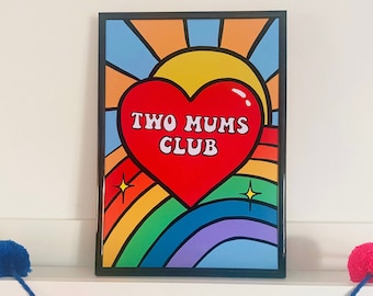 May include: A framed print with a rainbow background and a red heart with the text "TWO MUMS CLUB" in white. The heart is in front of a yellow sun with orange rays.