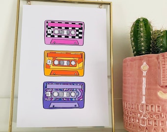May include: A framed print of three colorful cassette tapes with different patterns. The tapes are stacked vertically, with the top tape being pink, the middle tape being orange, and the bottom tape being purple.
