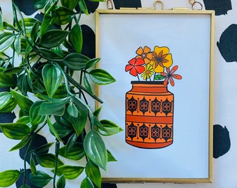 May include: A framed print of a vintage-style illustration of a vase with orange and yellow flowers. The vase has a geometric pattern in brown and orange.