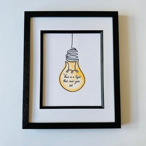 May include: A framed print with a yellow lightbulb illustration and the text "There is a light that never goes out".