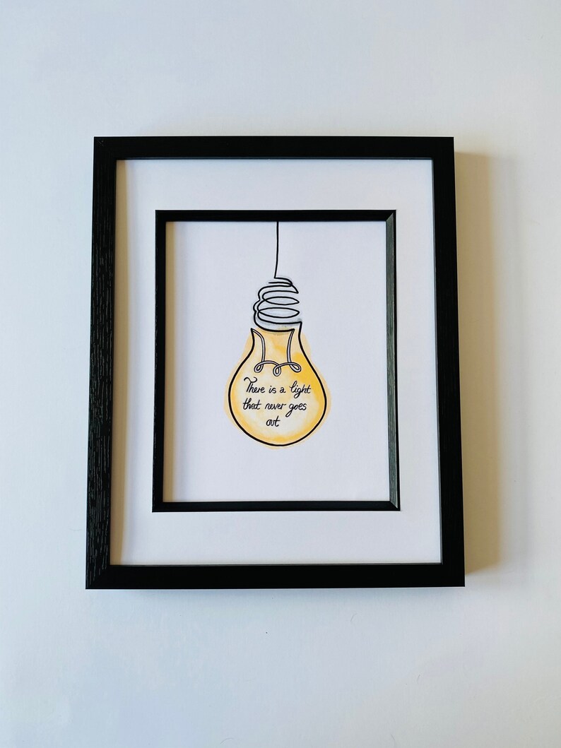 May include: A framed print with a yellow lightbulb illustration and the text "There is a light that never goes out".