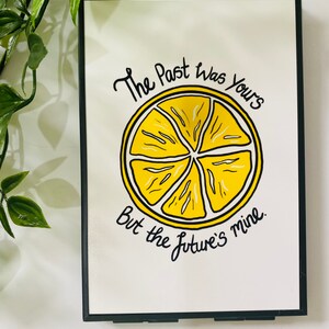 K&ouml;nnte beinhalten: Ein gerahmter Druck mit einer gelben Zitronenscheibe und dem Text "The Past Was Yours But The Future's Mine."