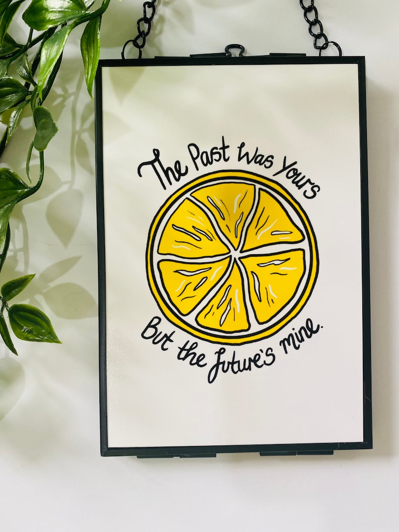 K&ouml;nnte beinhalten: Ein gerahmter Druck mit einer gelben Zitronenscheibe und dem Text "The Past Was Yours But The Future's Mine."