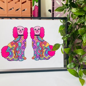 May include: A print of two psychedelic dogs with pink ears and collars. The dogs are outlined in black and have a colorful, swirling pattern.
