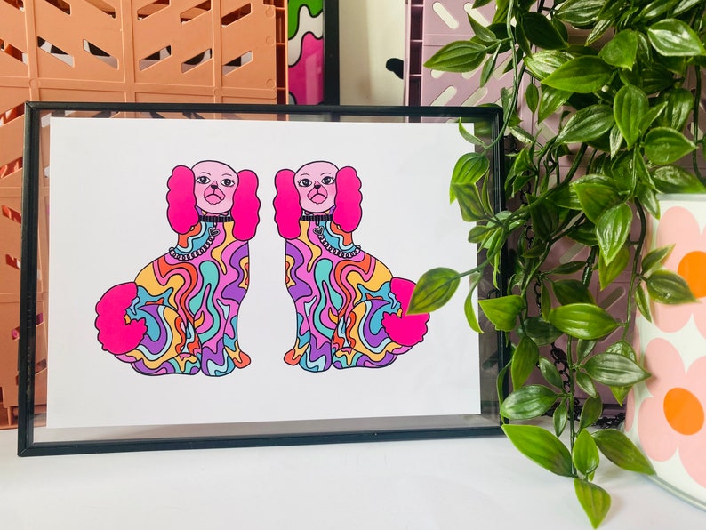 May include: A print of two psychedelic dogs with pink ears and collars. The dogs are outlined in black and have a colorful, swirling pattern.