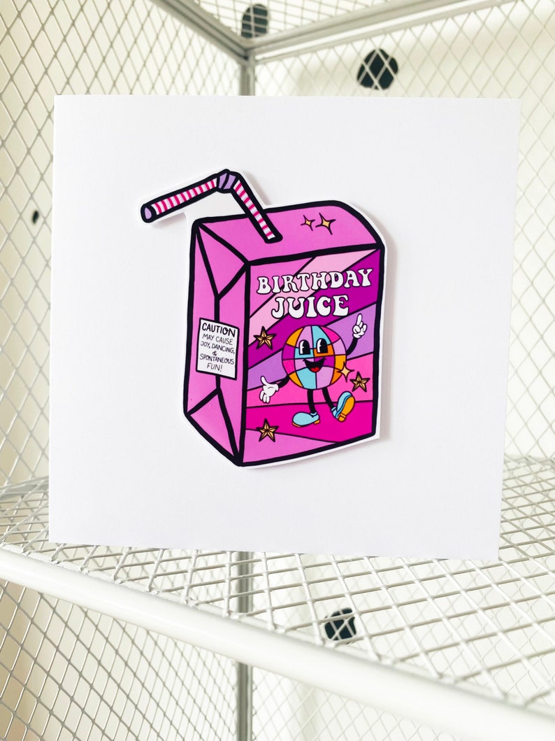 May include: A pink and purple birthday juice box with a cartoon character and the text "Birthday Juice". The box has a red and white striped straw.