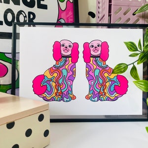 May include: A print of two psychedelic dogs with pink fur, rainbow swirls, and black collars. The dogs are facing forward and have their tongues sticking out.
