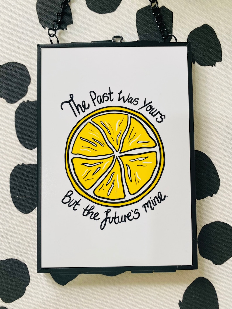 K&ouml;nnte beinhalten: Ein gerahmter Druck mit einer gelben Zitronenscheibe und dem Text "The past was yours but the future's mine."
