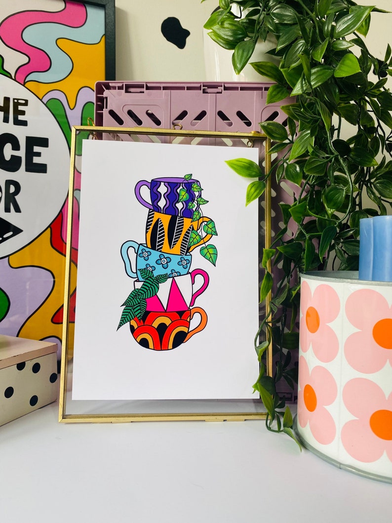 May include: A colorful illustration of a stack of four mugs with different patterns. The mugs are stacked on top of each other and have a leafy green plant growing out of the top mug.