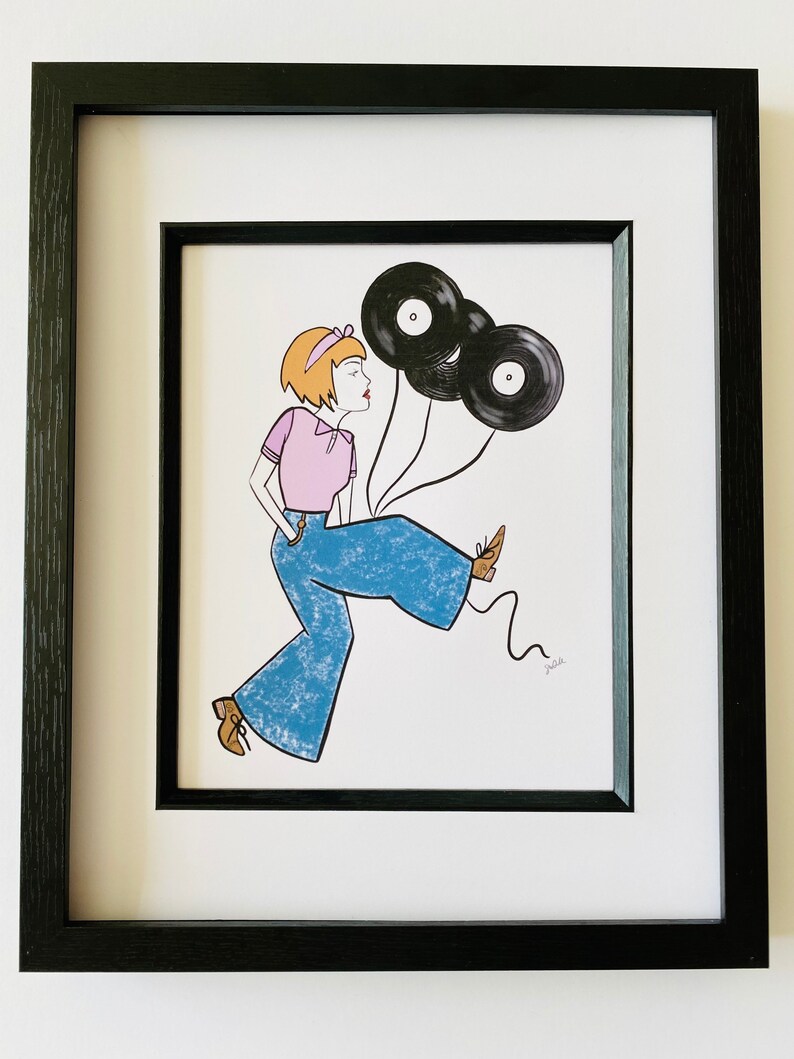 May include: A framed illustration of a woman with short blonde hair wearing a pink shirt and blue jeans. She is holding three black vinyl records as balloons. The illustration is signed "Julie".