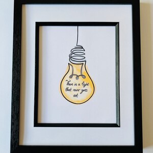 May include: A framed print with a yellow lightbulb illustration and the text "There is a light that never goes out."