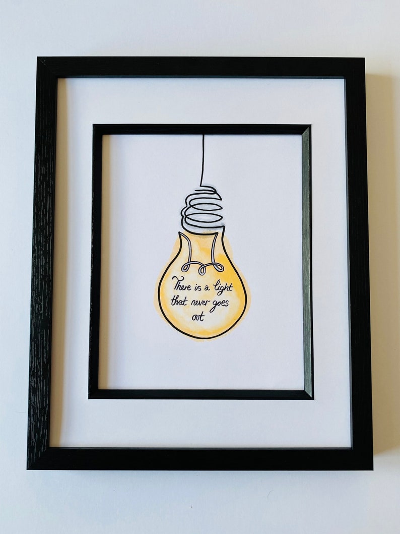 May include: A framed print with a yellow lightbulb illustration and the text "There is a light that never goes out."