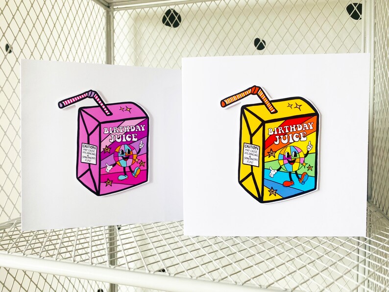 May include: Two illustrated cards with a cartoon juice box design. The juice box is yellow with a rainbow design and the text "Birthday Juice". The other juice box is pink with a rainbow design and the text "Birthday Juice".