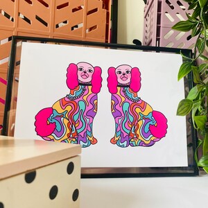 May include: A framed print of two psychedelic dogs with pink fur, colorful swirls, and black collars. The dogs are facing each other and have a similar design.