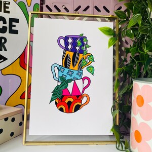 May include: A stack of four colorful mugs with different patterns, including a blue mug with white flowers, a yellow mug with black stripes, a purple mug with white waves, and a red and orange mug with a rainbow pattern. A green plant is growing out of the top mug.
