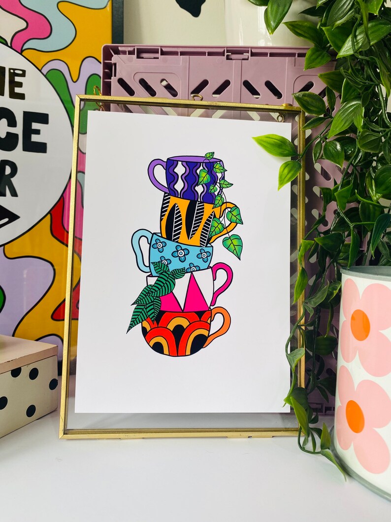 May include: A stack of four colorful mugs with different patterns, including a blue mug with white flowers, a yellow mug with black stripes, a purple mug with white waves, and a red and orange mug with a rainbow pattern. A green plant is growing out of the top mug.