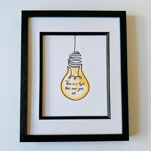 May include: A framed print with a yellow lightbulb illustration and the text "There is a light that never goes out".