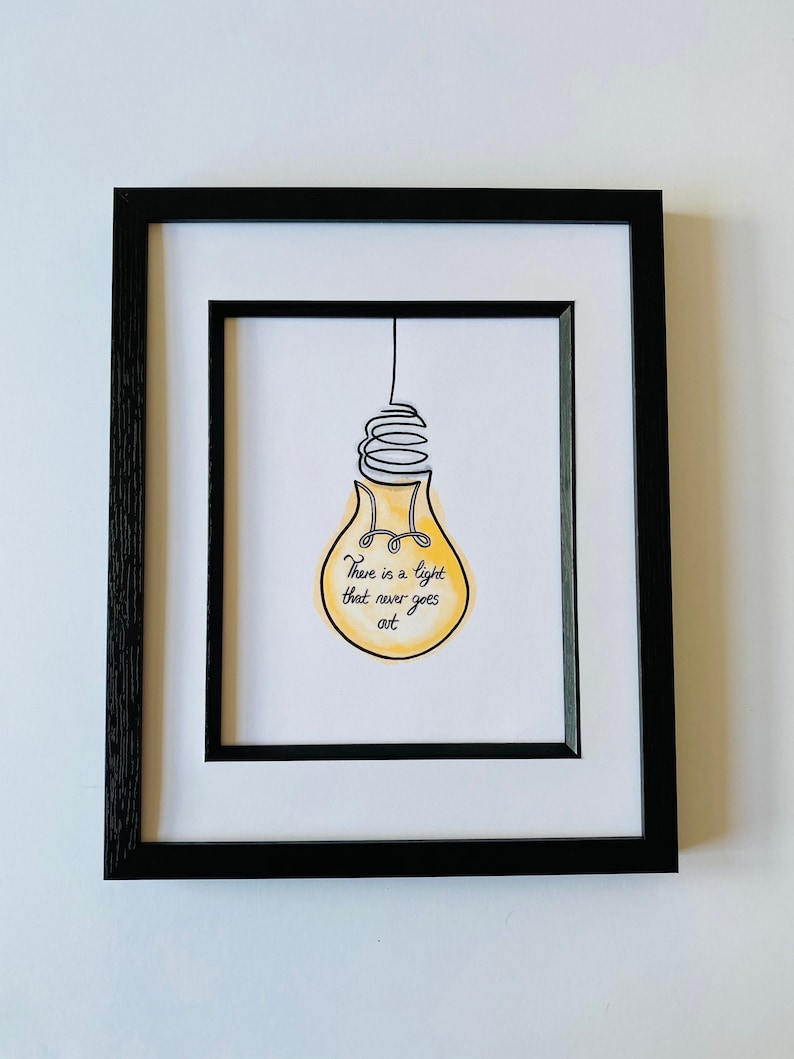 May include: A framed print with a yellow lightbulb illustration and the text "There is a light that never goes out".