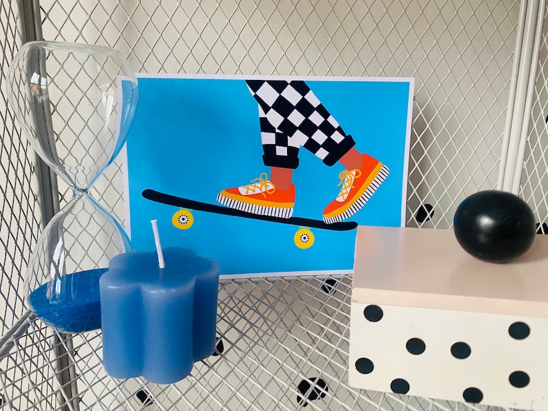 Pu&ograve; includere: Uno skateboard con stampa a scacchi blu e bianca con scarpe da ginnastica arancioni e gialle in cima. Lo skateboard &egrave; su uno sfondo blu con ruote gialle.