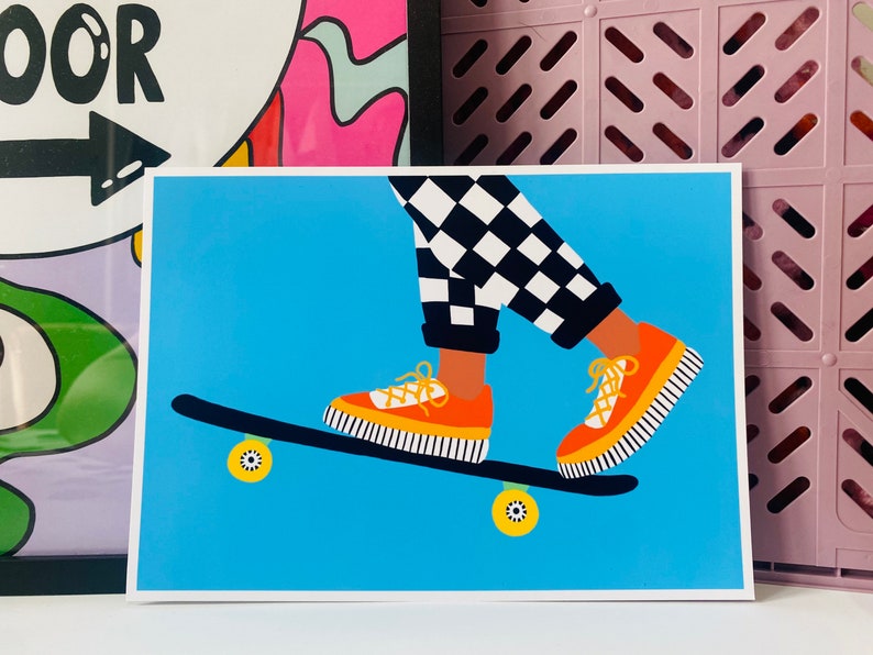 Pu&ograve; includere: Una persona con pantaloni a scacchi neri e bianchi sta facendo skateboard. Indossa scarpe arancioni con strisce nere. Lo skateboard &egrave; blu con ruote gialle.