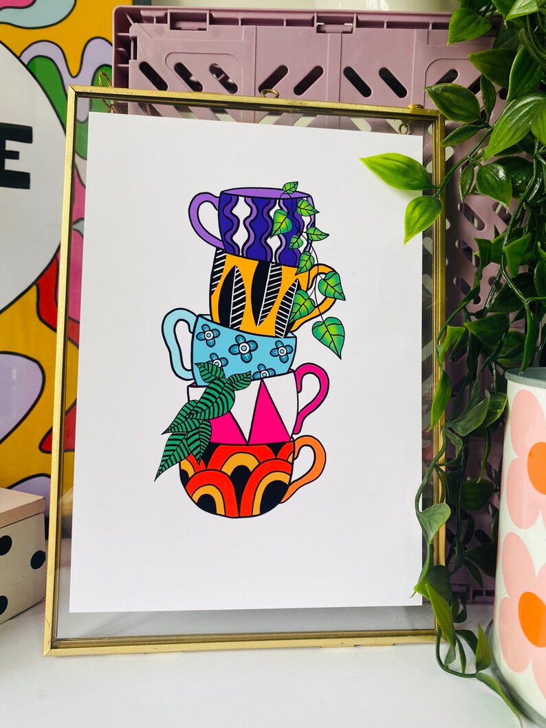 May include: A stack of four colorful mugs with different patterns, including wavy lines, flowers, and geometric shapes. The mugs are stacked on top of each other, with a green plant growing out of the top mug.