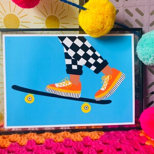 Pu&ograve; includere: Un'illustrazione incorniciata di una persona che fa skateboard. La persona indossa pantaloni a scacchi neri e bianchi e scarpe da ginnastica arancioni e nere. Lo skateboard &egrave; blu con ruote arancioni.