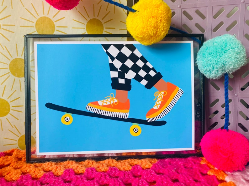 Pu&ograve; includere: Un'illustrazione incorniciata di una persona che fa skateboard. La persona indossa pantaloni a scacchi neri e bianchi e scarpe da ginnastica arancioni e nere. Lo skateboard &egrave; blu con ruote arancioni.