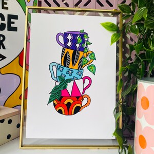 May include: A stack of four colorful mugs with geometric patterns and a leafy plant growing out of the top. The mugs are stacked in a tower, with the largest mug at the bottom and the smallest mug at the top. The mugs are all different colors and patterns, and the plant is green and leafy.