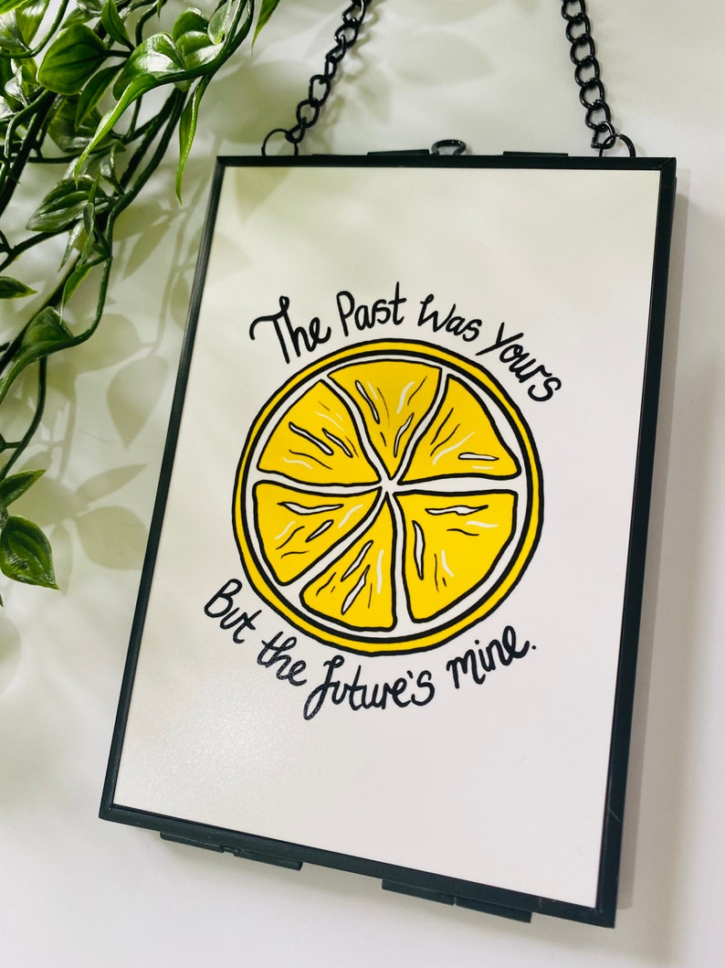 K&ouml;nnte beinhalten: Ein schwarzer gerahmter Druck mit einer gelben Zitronenscheibe und dem Text "The Past was Yours But the Future's mine."