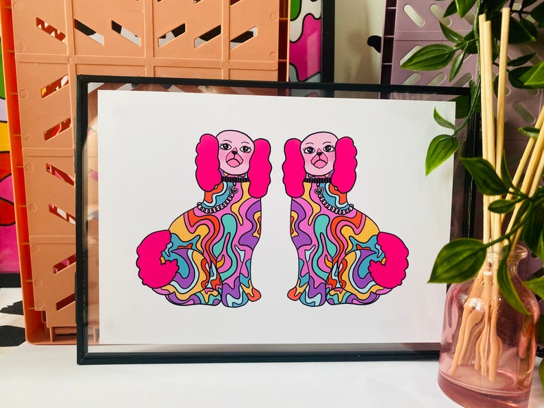May include: A framed print of two colorful, psychedelic dogs with pink fur and black collars. The dogs are facing forward and have a swirling, abstract pattern on their bodies.