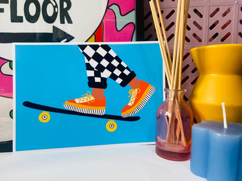 Pu&ograve; includere: Una gamba a scacchi blu e bianchi su uno skateboard con scarpe arancioni. Lo skateboard ha ruote gialle. Lo sfondo &egrave; di colore azzurro chiaro.
