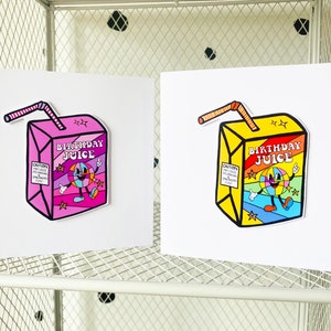 May include: Two greeting cards with illustrations of cartoon juice boxes. The juice boxes are pink and yellow with the words "Birthday Juice" on them. The juice boxes have a smiling cartoon face with a rainbow background.