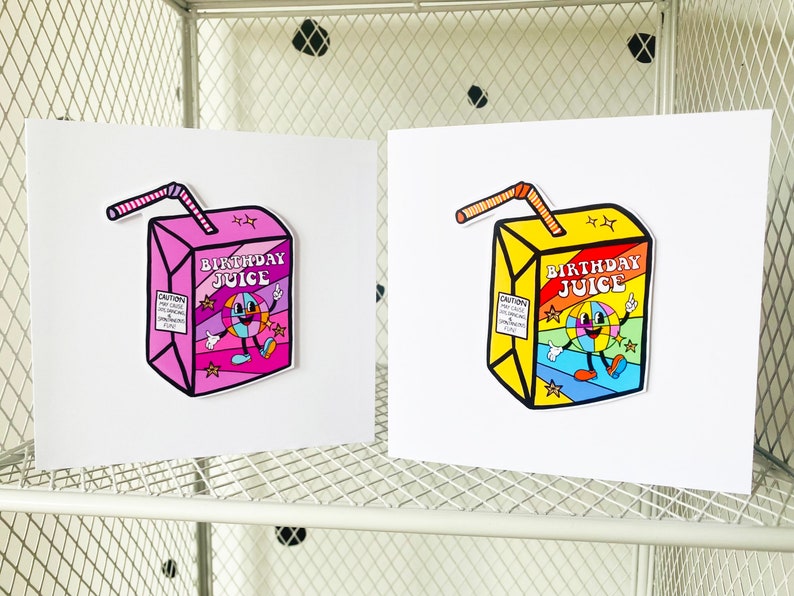 May include: Two greeting cards with illustrations of cartoon juice boxes. The juice boxes are pink and yellow with the words "Birthday Juice" on them. The juice boxes have a smiling cartoon face with a rainbow background.