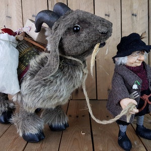 May include: A brown and gray stuffed goat with a white bag and other items on its back. A small, gray-haired gnome with a black hat and brown coat is holding a rope attached to the goat.