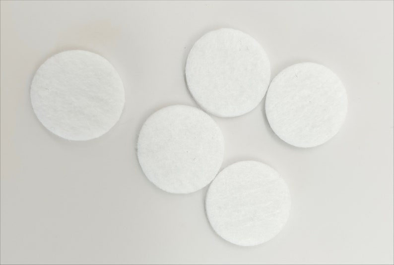 May include: Five white round felt pads, likely for furniture or other objects to prevent scratching.