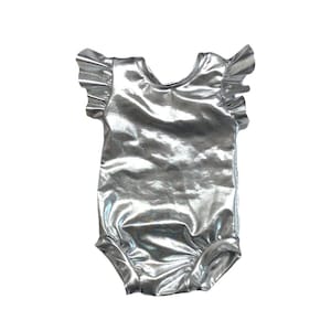 May include: A silver metallic bodysuit with ruffled sleeves. The bodysuit has a scoop neck and a snap closure at the bottom.
