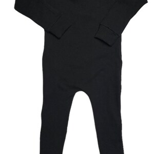 May include: A black long-sleeved jumpsuit with a scoop neck and ribbed fabric.