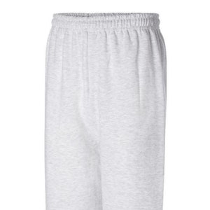 May include: Light gray sweatpants with an elastic waistband and cuffed ankles. The pants are made of a soft, comfortable material, perfect for casual wear or lounging. The neutral color makes them versatile for various outfits.