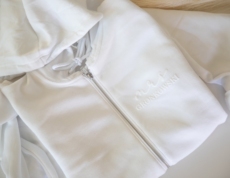 May include: White zippered hoodie with a white embroidered design that says "maxi Gronkowski"