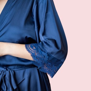 May include: A navy blue satin robe with lace trim on the sleeves.