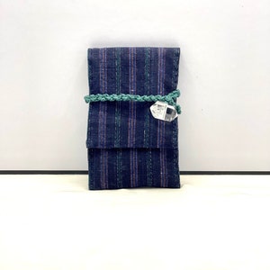 Op de afbeelding: Een blauwe en groene gestreepte stoffen tasje met een kristallen hanger. Het tasje is vastgebonden met een groen koord.