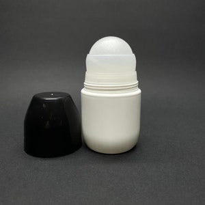 May include: A white roll-on deodorant container with a translucent applicator ball and a separate black cap. The cylindrical bottle features a smooth, opaque white finish, while the top section reveals a textured, frosted-look rolling sphere.