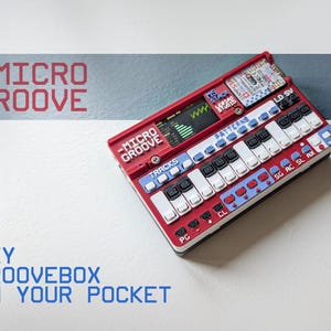 May include: A red and white portable electronic music synthesiser labelled Micro Groove. The device features a small digital screen, multiple white and black push buttons, and blue control panels with text including Tracks, Patterns, and various abbreviations.