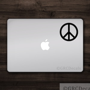 May include: A black peace sign sticker on a silver laptop.