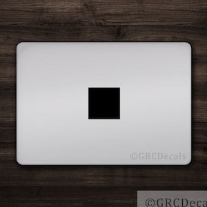 Op de afbeelding: Een zwarte vierkante sticker op een zilveren laptop.