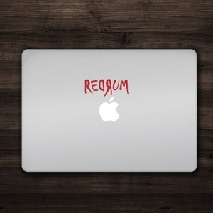 May include: A silver laptop with a red "REDRUM" sticker on the lid, with the Apple logo underneath.
