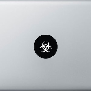 May include: A black circle sticker with a white biohazard symbol on a silver laptop.