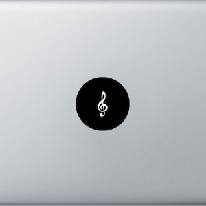 May include: A black circle sticker with a white treble clef symbol on a silver laptop.