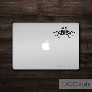 Op de afbeelding: Een zwart-witte sticker van de Vliegende Spaghettimonster, een fictieve godheid, op een zilveren laptop. De sticker toont het oog van de FSM met twee pupillen en noedel-achtige aanhangsels. De tekst "FSM" staat in het oog.